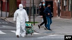 Žena u zaštitnom odijelu izlazi iz prodavnice u New Yorku (Foto: AFP/Johannes Eisele)