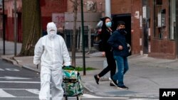 A woman wearing a hazmat suit and googles pulls her grocery cart in the streets in Queens, a borough of New York City, amid the coronavirus pandemic on April 20, 2020.