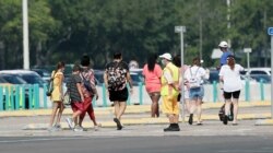 An attendant, front, directs park guests to the entrance of the Magic Kingdom during the reopening at Walt Disney World, July 11, 2020, in Lake Buena Vista, Fla.