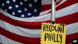 A sign hangs in front of an American flag, as a handful of supporters of President Donald Trump continue to protest outside the Pennsylvania Convention Center, in Philadelphia, November 10, 2020. 