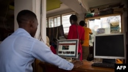 FILE - A man uses a computer to read news at a cyber cafe after the Uganda Communication Commission restored the internet in Kampala, Uganda.