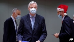 European Union chief negotiator Michel Barnier, center, carries a binder of the Brexit trade deal during a special meeting of Coreper, at the European Council building in Brussels, Dec. 25, 2020.