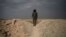 A U.S.-backed Syrian Democratic Forces (SDF) fighter stands atop a hill in the desert outside the village of Baghuz, Syria, Feb. 14, 2019. 