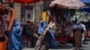 Burqa-clad Afghan women shop at a market area in Kabul on August 23, 2021, following the Taliban's military takeover of the country.
