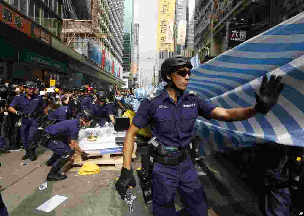Police officers clear a protest site after warning the crowd that they would start enforcing the court-ordered clearing of the occupied area in the Mong Kok district of Hong Kong, Nov. 26, 2014.