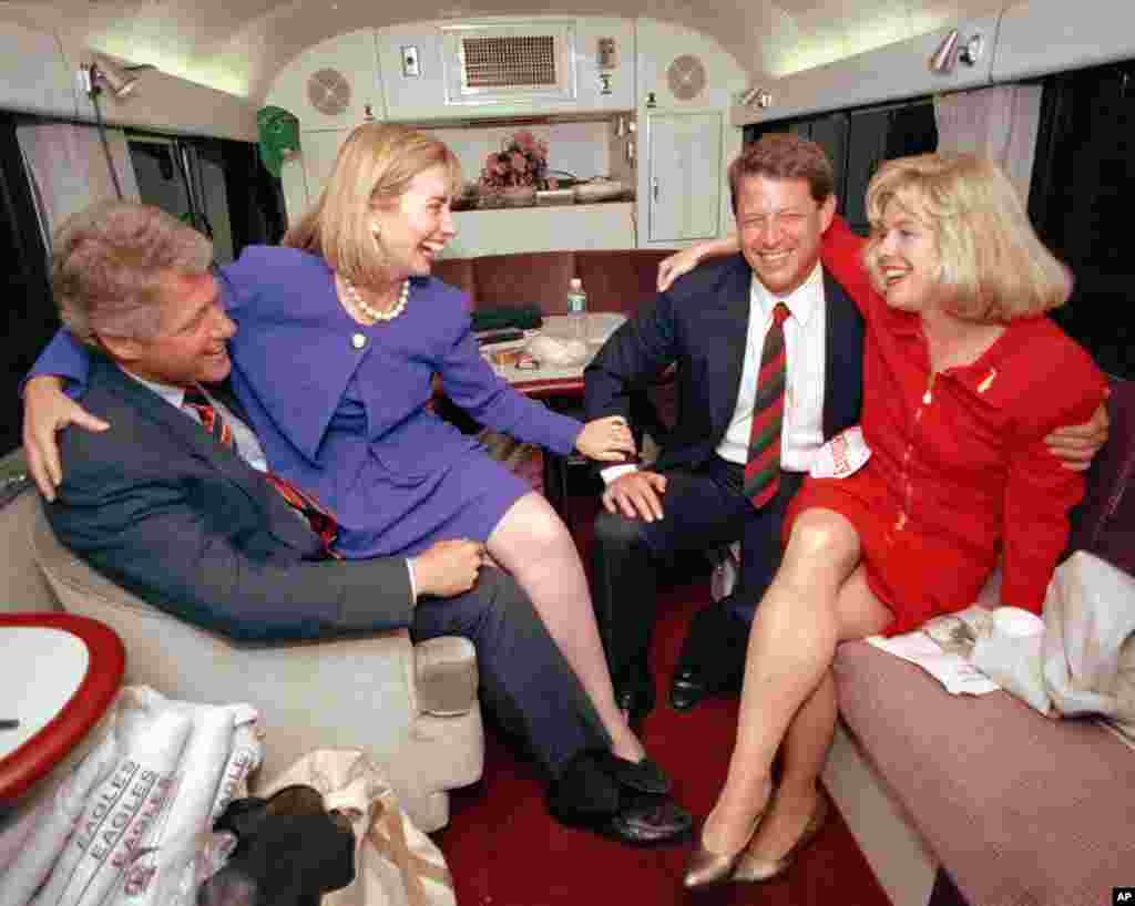 Hillary Rodham Clinton sits on the lap of her husband, democratic presidential candidate Bill Clinton left, as she jokes with vice presidential candidate Al Gore and his wife, Tipper, during a brief rest on their bus in Durham, N.C., Monday, Oct. 26, 1992