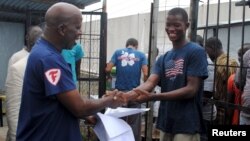 Cassius Kollie (phải), 24 tuổi, một trong bốn người được xuất viện vào hôm thứ Hai từ một đơn vị điều trị Ebola, nhận giấy chứng nhận đã khỏi bệnh ở Paynesville, Liberia, ngày 20/7/2015.