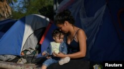 En esta foto de archivo, una madre y su hija permanecen en un campamento improvisado ocupado por solicitantes de asilo rechazados por Estados Unidos, en Tamaulipas, México, el 27 de octubre de 2019.