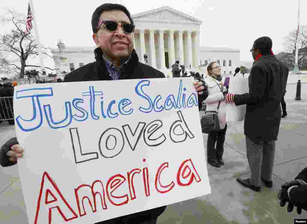 Jose Fernandez stands outside the U.S. Supreme Court building with a sign reading "Justice Scalia Loved America" shortly after the casket of Scalia arrived at the court to lie in repose in Washington, Feb. 19, 2016. 