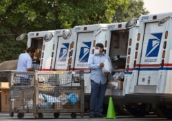 FILE - Postal workers load packages in their mail delivery vehicles at the Panorama city post office on Aug. 20, 2020 in the Panorama City section of Los Angeles.