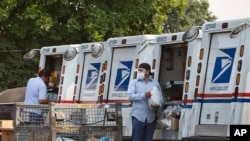FILE - Postal workers load packages in their mail delivery vehicles at the Panorama city post office on Aug. 20, 2020, in the Panorama City section of Los Angeles.