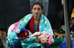 A Venezuelan migrant woman holds a baby outside an immigration processing office on the Rumichaca bridge after crossing the border from Colombia to Rumichaca, Ecuador, June 12, 2019.