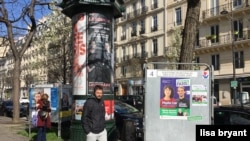 A man walks past campaign posters in Paris, March 15, 2020. (L. Bryant/VOA)