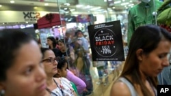 Shoppers walk past a sign promoting Black Friday sales at the Sambil shopping center in Caracas, Venezuela, Nov. 29, 2019.