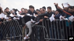 Migrants wait behind bars to have errors in their transit documents corrected by Greek authorities at a camp in Idomeni, on the Greek-Macedonian border, March 3, 2016. 