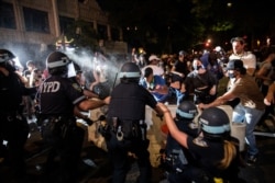 A police officer sprays protesters in the Brooklyn borough of New York City during a march against the death of George Floyd in Minneapolis police custody, May 30, 2020.