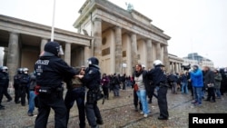Demonstrators are detained by police officers during a protest against the government's coronavirus disease (COVID-19) restrictions, next to the Brandenburger Gate in Berlin, Nov. 18, 2020.
