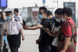 A man wears a face mask as he scans a code before entering the Wuhan Railway Station, in China's central Hubei province on May 28, 2020.