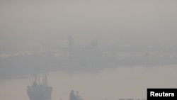 FILE - A cargo ship is seen through air pollution along the Chao Phraya river in Bangkok, Thailand, Jan. 11, 2019. 