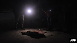 FILE - Somali security officers look at the body of a suspected al-Shabab fighter in Mogadishu, Somalia, Nov. 5, 2016. The U.S. military says it has killed six al-Shabab members in its fourth airstrike this week.