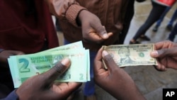 Zimbabweans compare the new note with the U.S. dollar note following the introduction of new notes by the Reserve Bank of Zimbabwe in Harare, Nov, 28, 2016. 