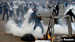 An anti-government protester throws a teargas canister back at police during riots at Altamira square in Caracas, March 6, 2014. 