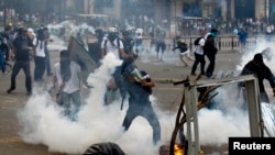 FILE - An anti-government protester throws a teargas canister back at police during riots at Altamira square in Caracas, Venezuela, March 6, 2014. 