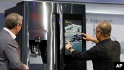 Yoon Lee, right, senior vice president, Samsung Electronics America, uses the Family Board on a refrigerator during a Samsung news conference at CES International in Las Vegas, Jan. 7, 2019.