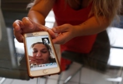 Barbara Rodriguez shows a photograph on her phone of her talking to her husband, Pablo Sanchez, at her home in Hialeah, Fla., Aug. 6, 2019.