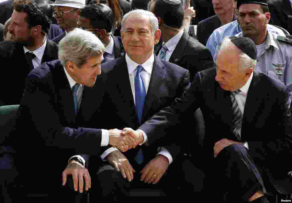 Israeli President Shimon Peres shakes hands with U.S. Secretary of State John Kerry as Prime Minister Benjamin Netanyahu sits between them during a ceremony marking Israel&#39;s annual day of Holocaust remembrance, at Yad Vashem, Jerusalem, April 8, 2013.