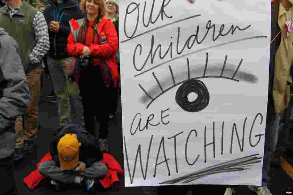 A young boy sits at the feet of his mother at the Women’s March in Washington, D.C., Jan. 21, 2017. (E. Sarai/VOA)