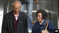 An elderly couple hold their grandson's hands as they enter a subway station in People's Square, Shanghai April 28, 2011.