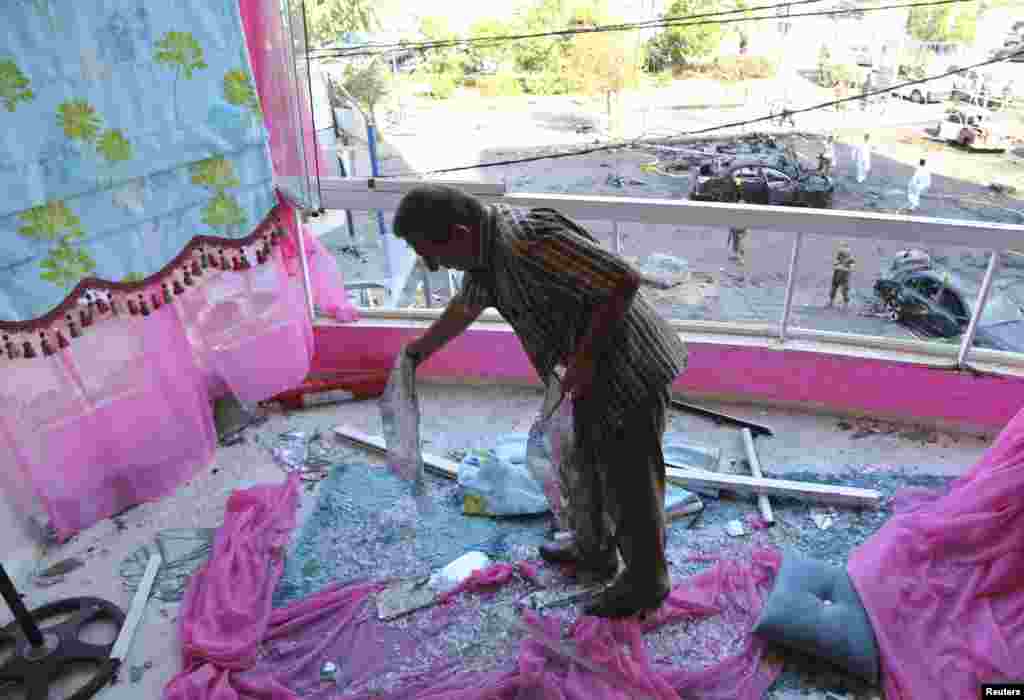 A man cleans shattered glass from his balcony after an explosion in the southern suburbs of Beirut, June 24, 2014.