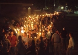 FILE - White nationalists carry torches on the grounds of the University of Virginia, on the eve of a "Unite the Right" rally in Charlottesville, Virginia, Aug. 11, 2017.