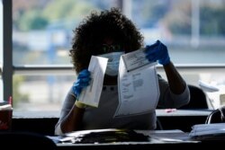 An election worker examines a ballot as vote counting in the general election continues at State Farm Arena in Atlanta, Georgia, Nov. 4, 2020.