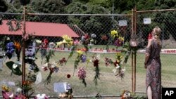 A woman places flowers on a fence at the waterfront in Whakatane, New Zealand, Dec. 11, 2019. 