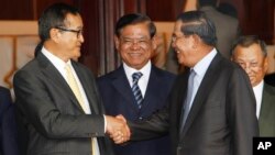 Cambodian Prime Minister Hun Sen, second from right, shakes hands with the main opposition party leader Sam Rainsy, left, of Cambodia National Rescue Party, as Deputy Prime Minister Sar Kheng, second from left, looks on after a meeting in Senate headquarter, Phnom Penh, Cambodia. 