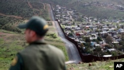 FILE - Border Patrol agent Vincent Pirro looks on near a border wall that separates the cities of Tijuana, Mexico, and San Diego, Feb. 5, 2019, in San Diego, California. 