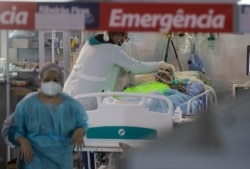 FILE - Health workers treat a COVID-19 patient at the emergency unit of a field hospital set up to treat COVID patients in Ribeirao Pires, greater Sao Paulo area, Brazil, April 13, 2021.