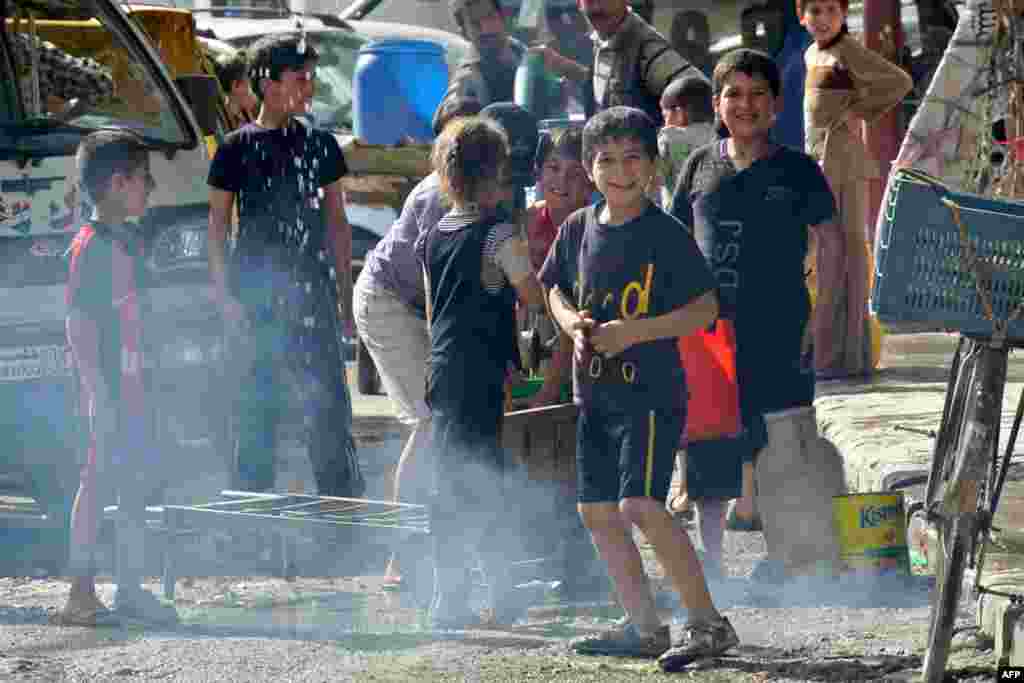 Syrian children play near a water distribution point in the Almyassar central district of Aleppo, May 8, 2013.