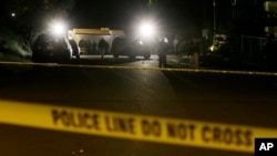 FILE - Crime-scene tape is shown as investigators work under lights at the scene of an overnight shooting.