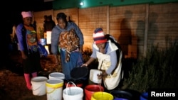 FILE - Residents collect water at night from an electric-powered well, as the country faces 18-hour daily power cuts, in a suburb of Harare, Zimbabwe, July 30, 2019.