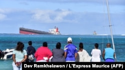 Des passants regardent le vraquier MV Wakashio qui s'était échoué près du parc marin de Blue Bay, dans le sud-est de l'île Maurice, le 6 août 2020. (Photo: Dev Ramkhelawon / L'Express Maurice / AFP)