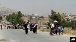 FILE - Syrians carry supplies as they return to the rebel-held Damascus suburb of Moadamiyeh near Damascus, July 14, 2014. A protest in 2011 sparked a civil war that has killed more than 300,000 people and displaced more than 13 million people at home and abroad.