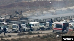 Forces loyal to Syria's President Bashar al-Assad sit on a tank as a convoy bringing people out of eastern Aleppo turns back in the direction of the besieged rebel enclave, Syria Dec. 16, 2016.