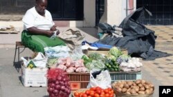 FILE - A woman roadside vegetable vendor displays her goods as the price of vegetables has doubled along with other foodstuffs since election day in Nairobi, Kenya, March 7, 2013.