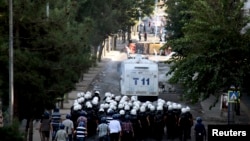 Kurdish protesters throw stones as they clash with riot police (foreground) in Diyarbakir, Turkey, Oct. 8, 2014.