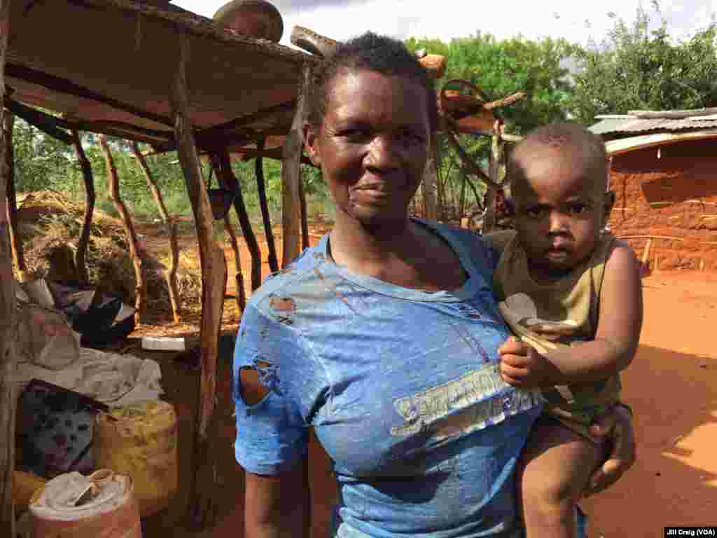 Charity Mwangome, holding her grandson, uses a beehive fence to protect her crops from elephants, on her farm in Taita-Taveta area, Kenya, April 19, 2016.