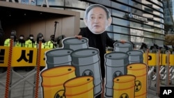A member of youth groups wearing a cutout of Japanese Prime Minister Yoshihide Suga performs to denounce his government's decision to release treated radioactive water, in Seoul, South Korea, April 13, 2021.