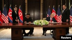 U.S. President Donald Trump and North Korea's leader Kim Jong Un sign documents that acknowledge the progress of the talks and pledge to keep momentum going, after their summit at the Capella Hotel on Sentosa island in Singapore, June 12, 2018. 